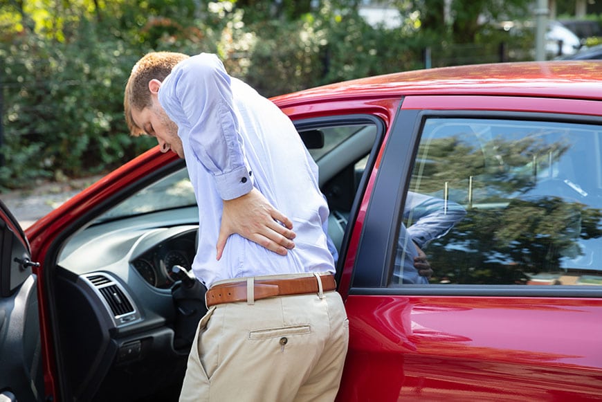 man with back pain get into car